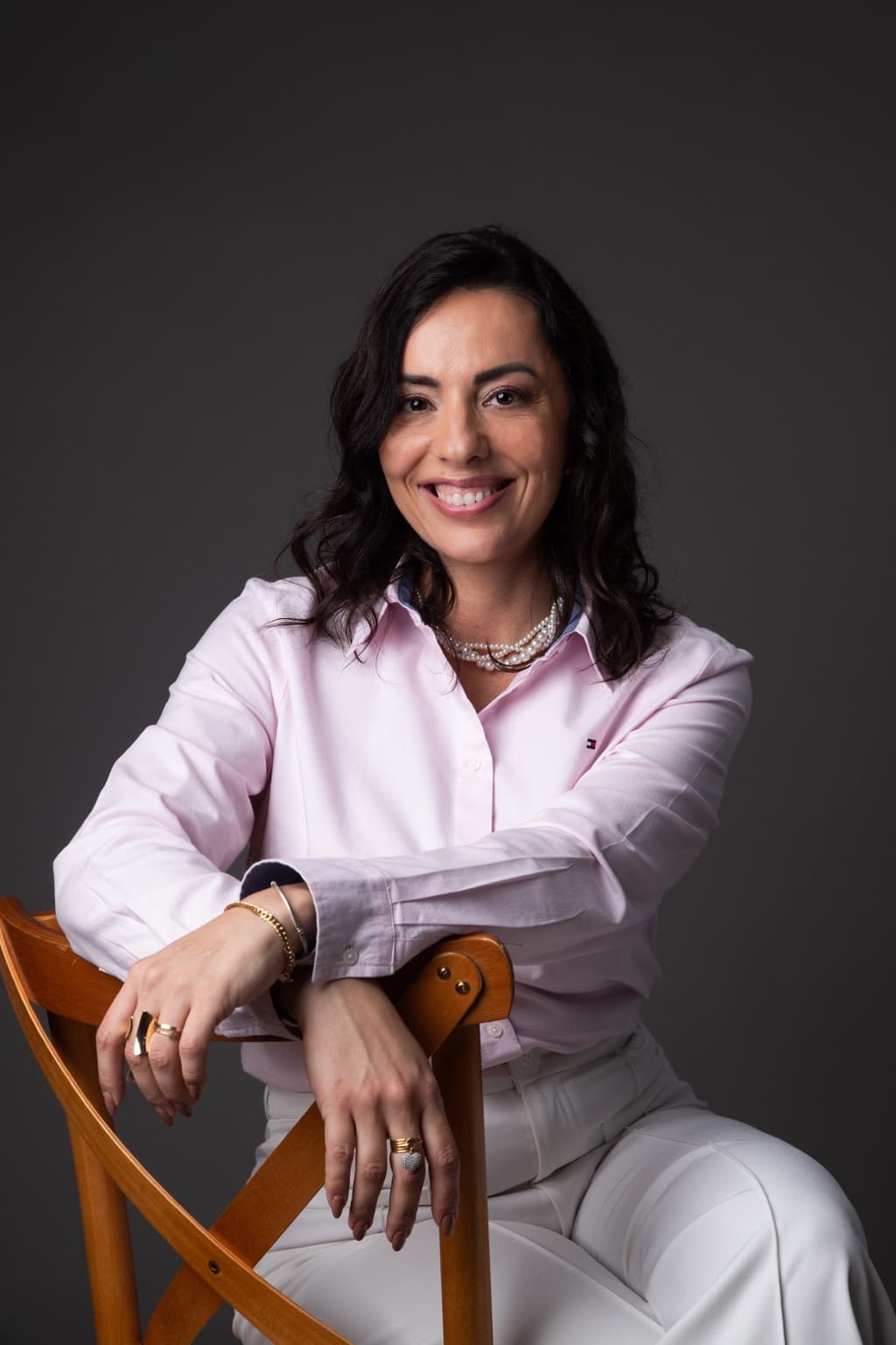 Monique Fernandes sorrindo, vestindo camisa rosa